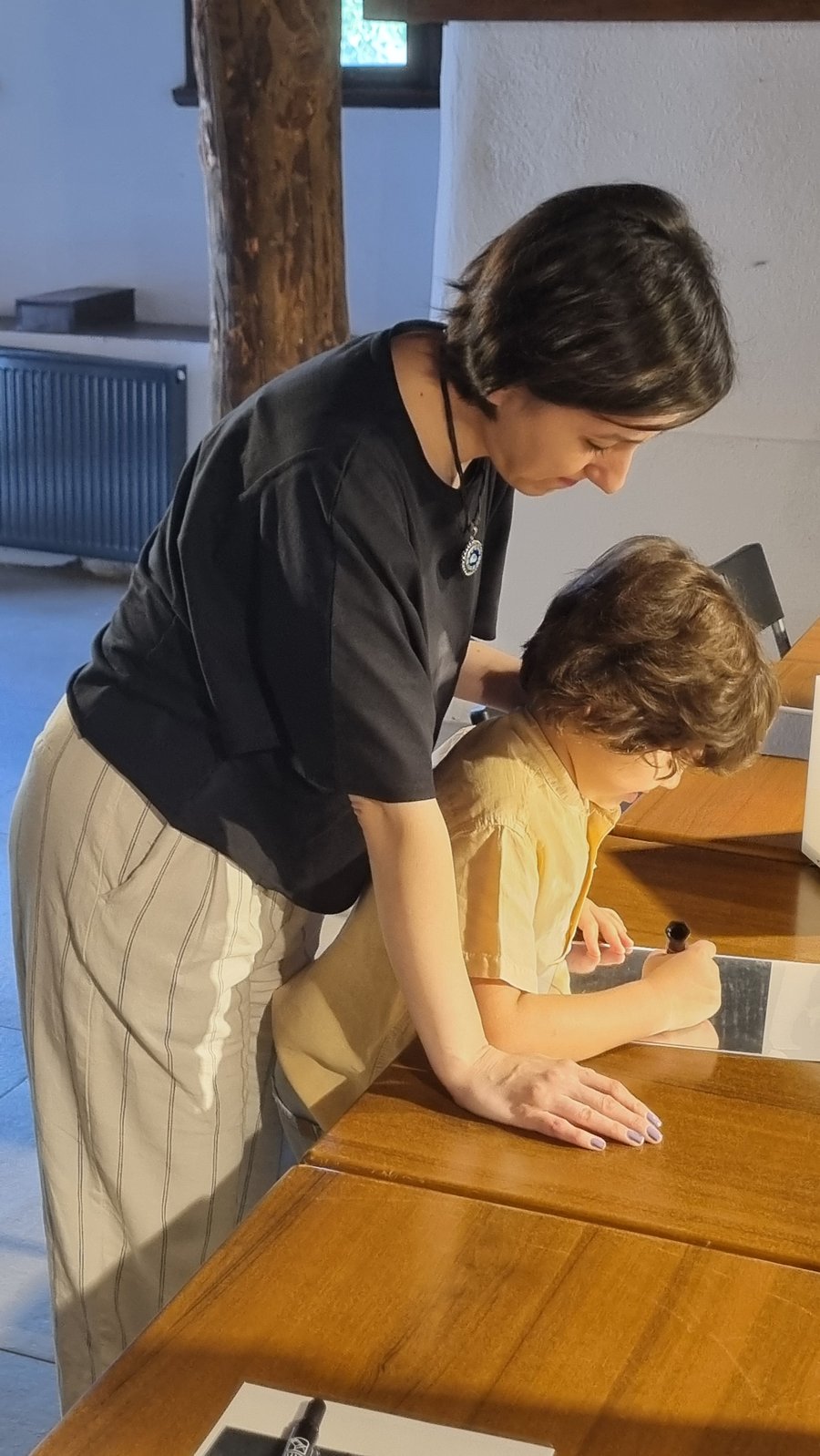 Eğitmen, kendi atölyesini oluşturan bir öğrenciye masada rehberlik ediyor
